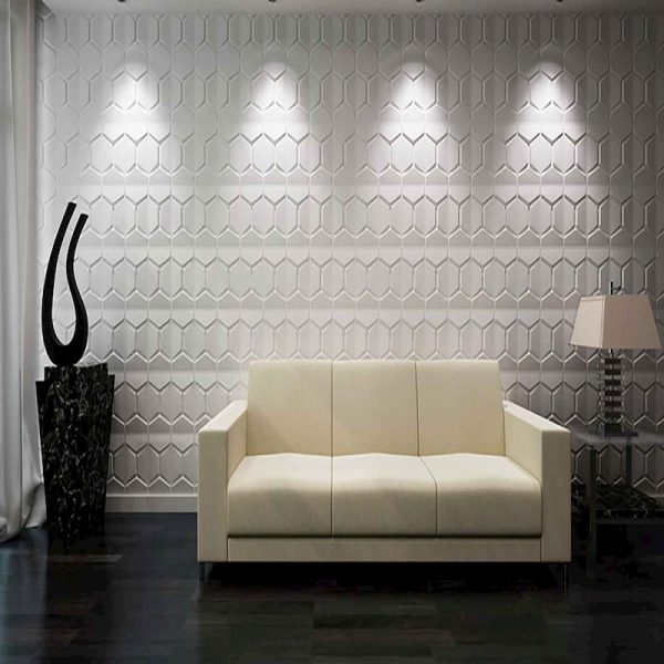 Es una habitación donde las paredes están decoradas con diseños tridimensionales que tienen forma de diamantes. Además, hay un sofá blanco en la sala que resalta por su simplicidad y elegancia.