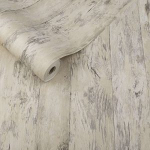 Es un rollo de papel tapiz que se ve como madera clara con diseños de paneles. El rollo de papel tapiz está situado en un suelo hecho también de madera.