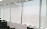 Es una habitación amplia que se utiliza como oficina. Las ventanas están cubiertas con cortinas enrollables, que puedes subir o bajar para ajustar la cantidad de luz que entra. Hay un escritorio grande en la habitación donde puedes trabajar.