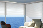 Una sala de estar que tiene Cortinas Venecianas a través de las cuales se puede ver el océano.